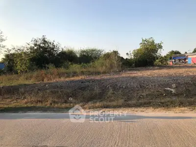 Vacant land plot with potential for development, surrounded by greenery and clear skies.