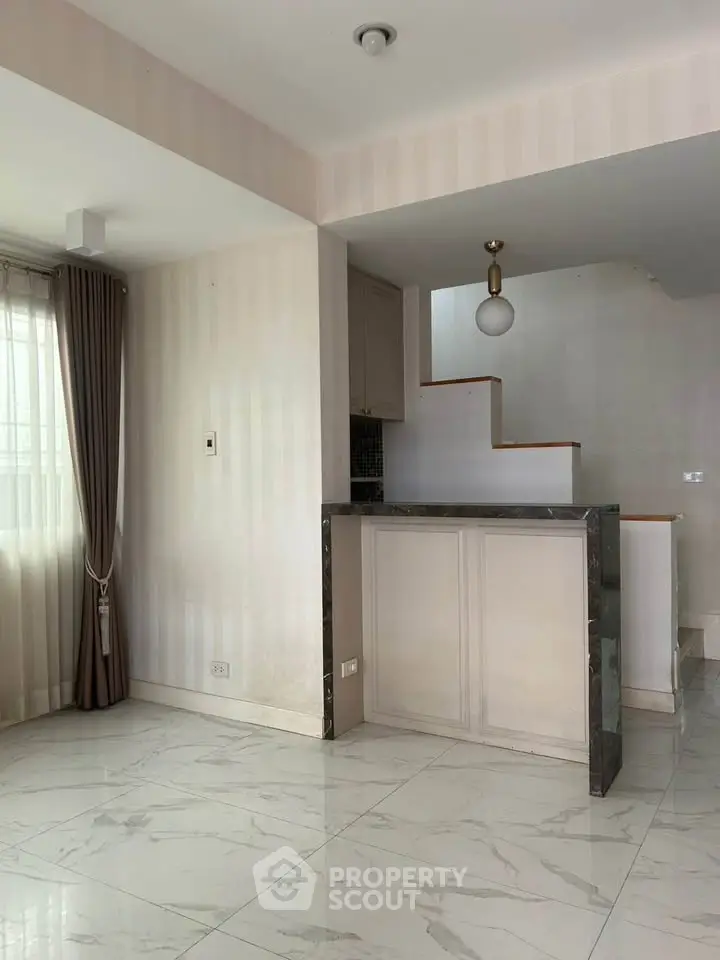 Modern interior with marble flooring and elegant staircase in a bright living space.