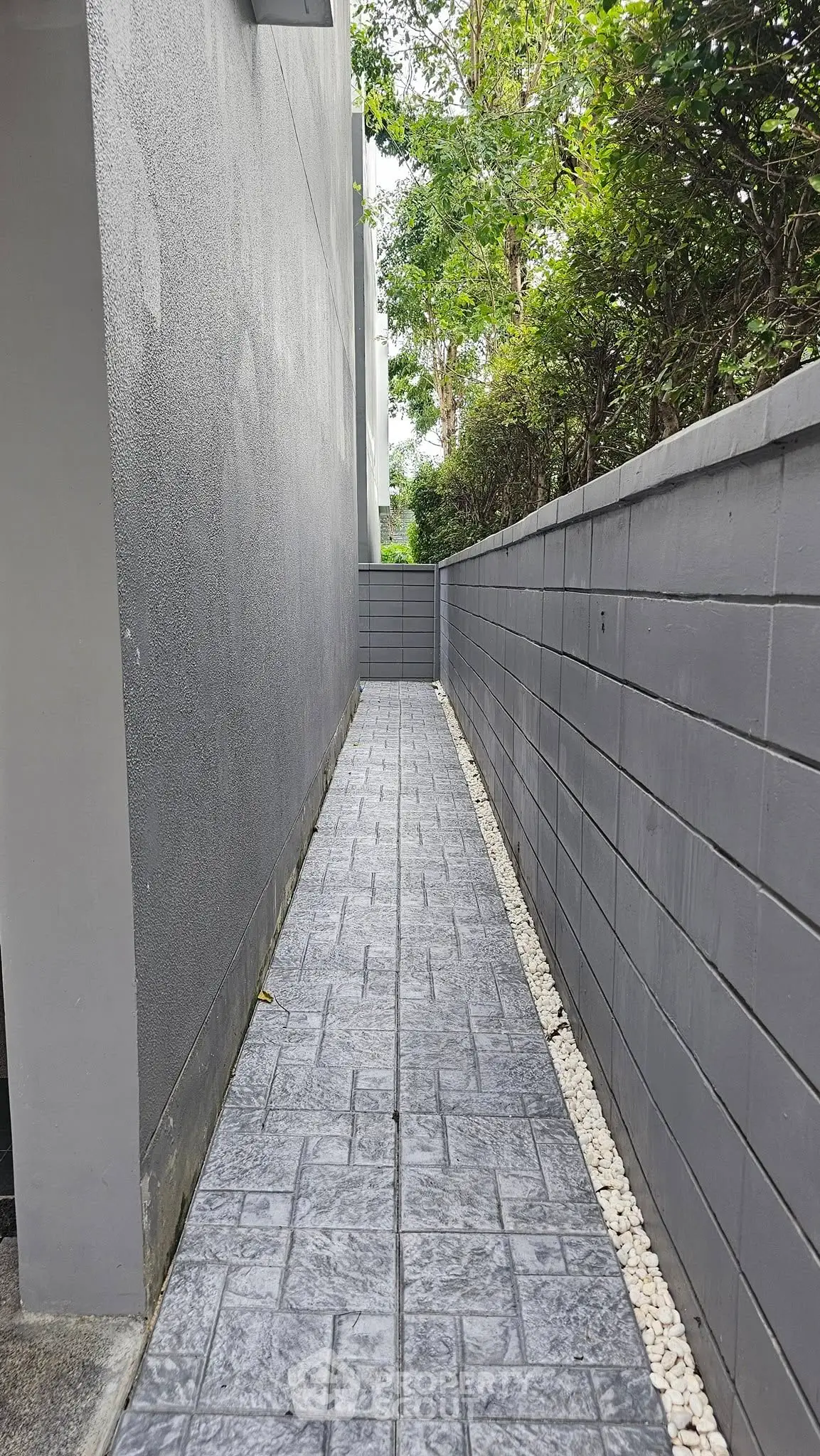 Narrow outdoor pathway with modern gray walls and stone flooring