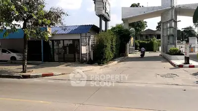 Charming entrance to a residential complex with lush greenery and modern architecture.