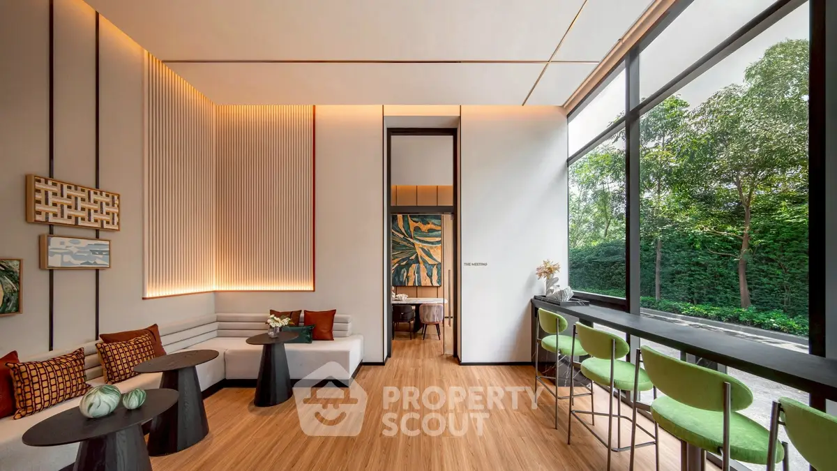 Modern living room with large windows and stylish decor, featuring a cozy seating area and natural light.