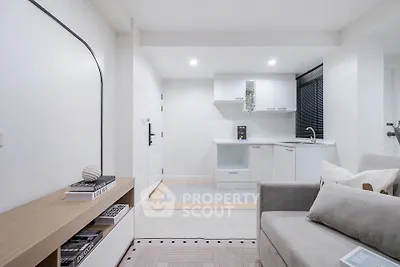 Modern minimalist living room with open kitchen layout and sleek white cabinetry.