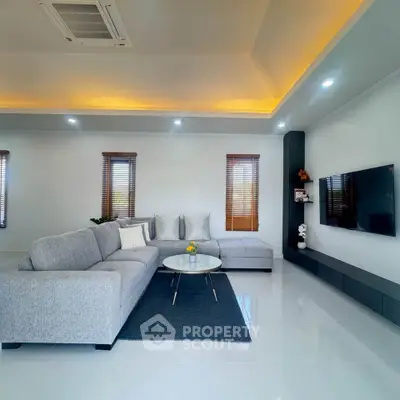 Spacious modern living room with elegant grey sectional sofa and wall-mounted TV.