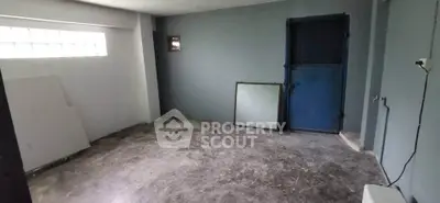 Spacious unfinished room with concrete floor and blue door, ideal for customization.
