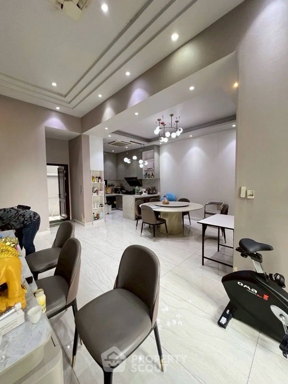 Spacious modern dining area with open kitchen and exercise bike, perfect for contemporary living.