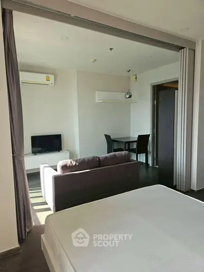 Modern studio apartment with open layout, featuring a cozy living area and sleek furniture.