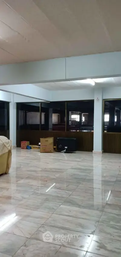 Spacious open-plan living area with marble flooring and large windows, ideal for modern living.