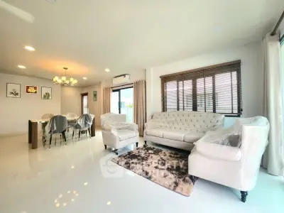 Spacious living room with elegant furniture and dining area, featuring large windows and modern lighting.