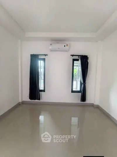 Spacious unfurnished room with air conditioning and large windows, perfect for customization.