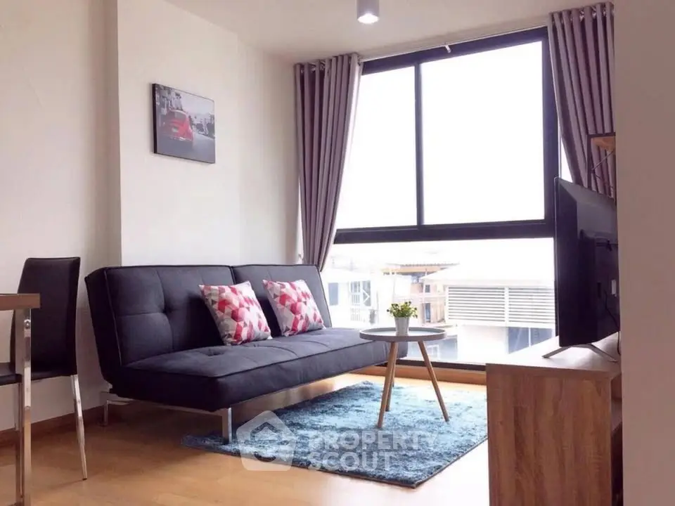 Modern living room with stylish sofa, large window, and chic decor in a bright apartment.