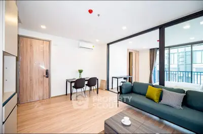 Modern living room with balcony view, stylish furniture, and open layout in urban apartment.