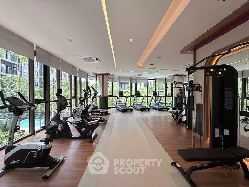 Luxurious gym with modern equipment and pool view in upscale residential building.