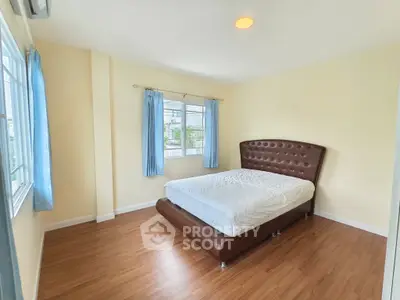 Bright bedroom with large windows and modern bed frame in a cozy apartment.