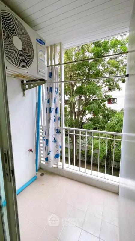 Charming balcony with lush green view and air conditioning unit, perfect for relaxation.