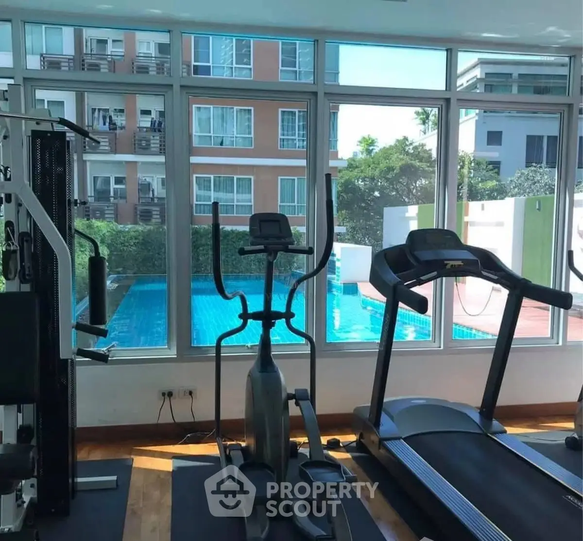Modern gym with pool view in luxury apartment complex