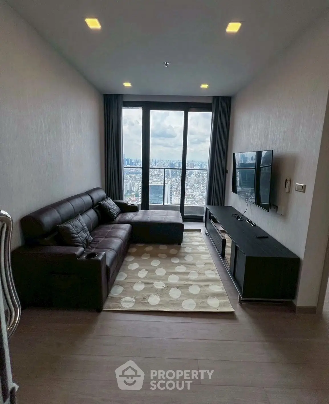 Modern living room with city view, featuring sleek furniture and large windows.