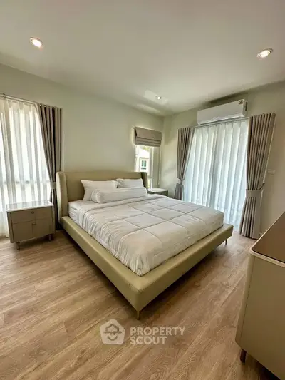 Spacious bedroom with modern decor and large windows for natural light.