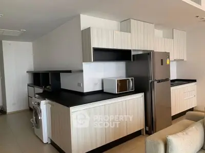 Modern kitchen with sleek cabinetry, stainless steel fridge, and washing machine in open layout design.