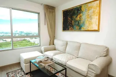 Bright living room with a large window offering a stunning city view, cozy beige sofa, and elegant artwork.