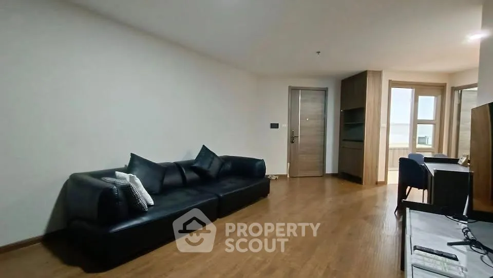 Spacious modern living room with sleek black sofa and wooden flooring