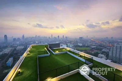 Stunning rooftop view with lush green terrace overlooking city skyline at sunset.