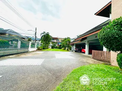 Spacious driveway leading to a modern residential building with lush greenery and ample parking space.