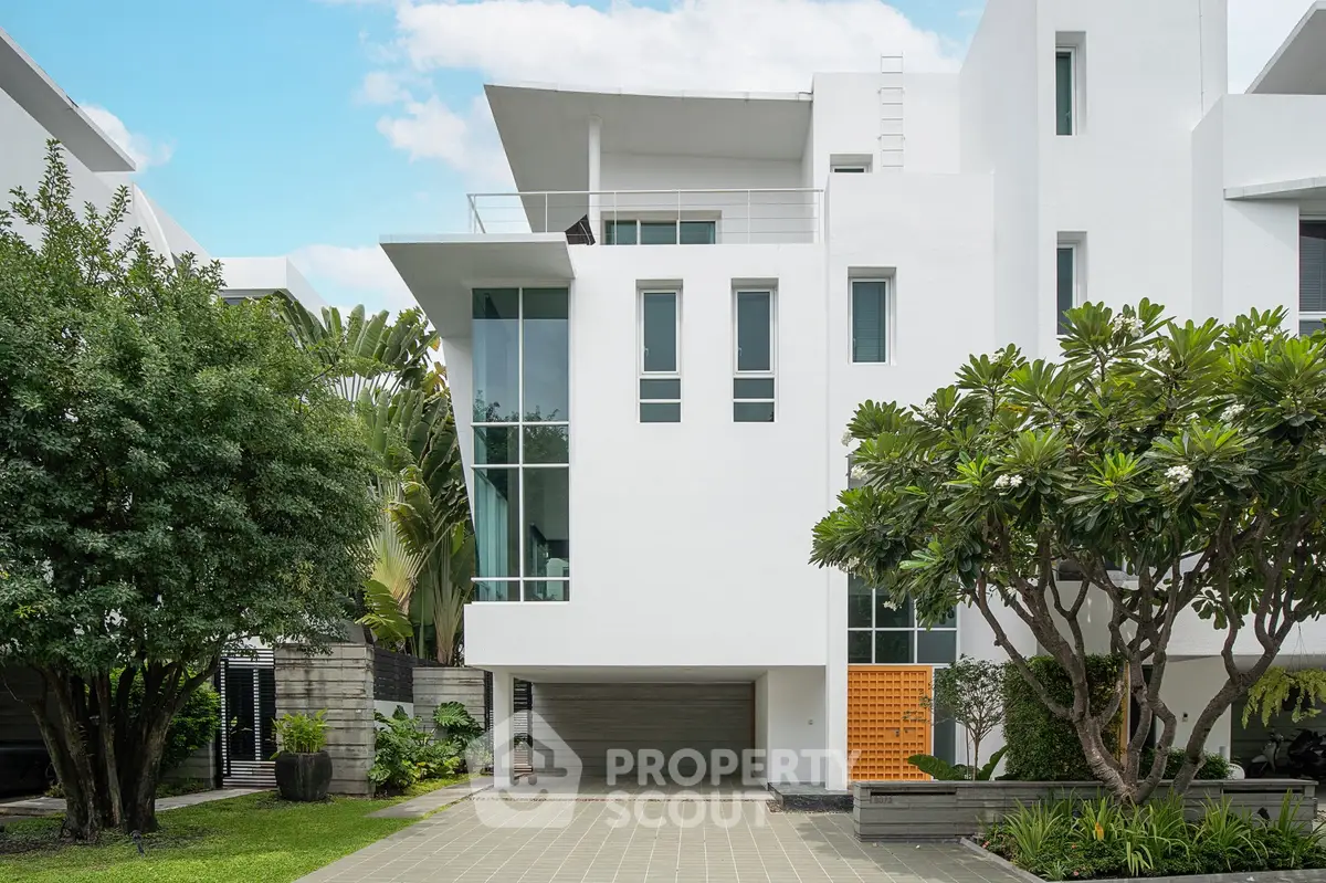 Modern white building exterior with lush greenery and spacious driveway