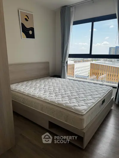 Modern bedroom with large window and city view, featuring a comfortable bed and stylish decor.