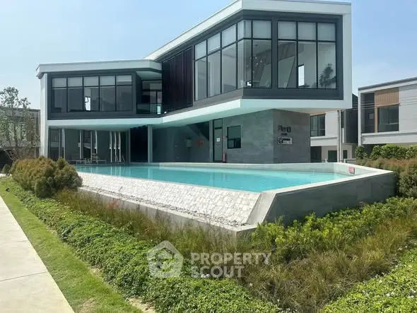 Modern luxury building with sleek design and stunning pool in lush green surroundings.