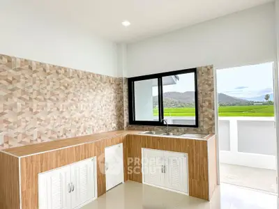 Modern kitchen with open layout and scenic view of lush green fields.