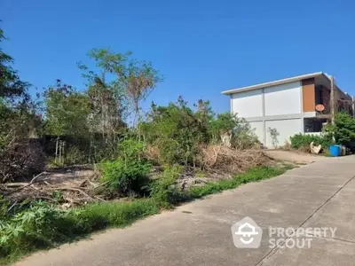 Spacious outdoor area with potential for landscaping adjacent to a modern structure with clear skies, ideal for a custom garden or outdoor living space.