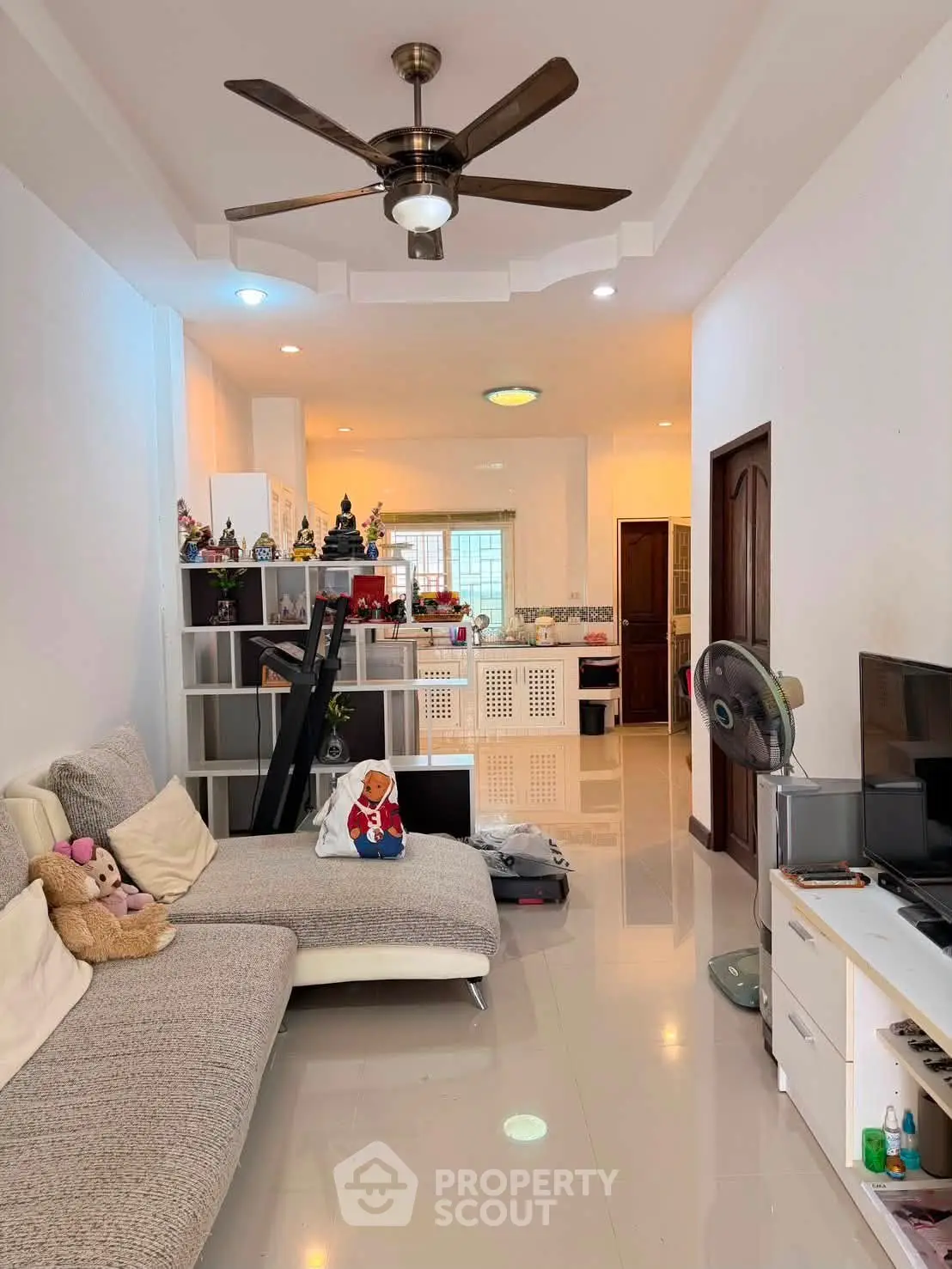 Spacious living room with modern decor and ceiling fan, perfect for family gatherings.