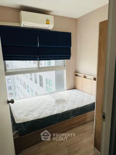 Cozy bedroom with natural light and modern air conditioning unit, perfect for urban living.