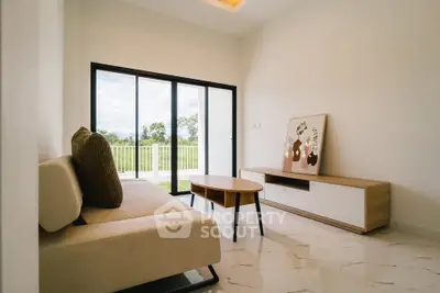 Modern living room with sleek furniture and large glass doors opening to a scenic view.