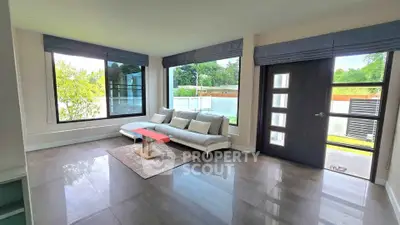 Spacious modern living room with large windows and stylish furniture, offering a bright and inviting atmosphere.