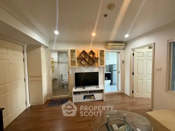 Cozy living room with wooden flooring and built-in TV unit in modern apartment.