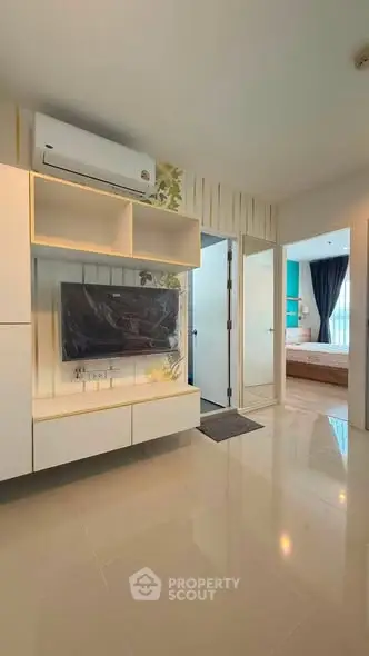 Modern living room with sleek TV setup and view into a stylish bedroom