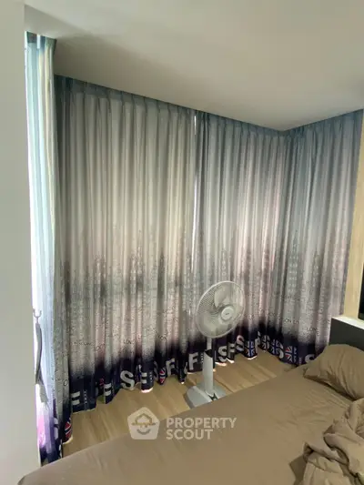 Cozy bedroom with elegant curtains and a fan, perfect for relaxation.