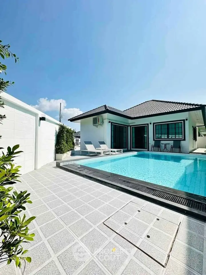 Stunning modern villa with private pool and spacious patio under clear blue sky.