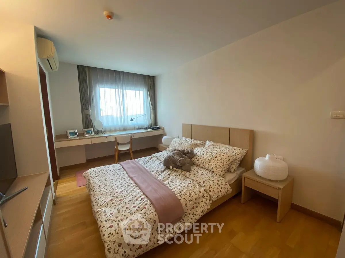 Cozy bedroom with stylish decor and natural light, featuring a comfortable bed and functional workspace.