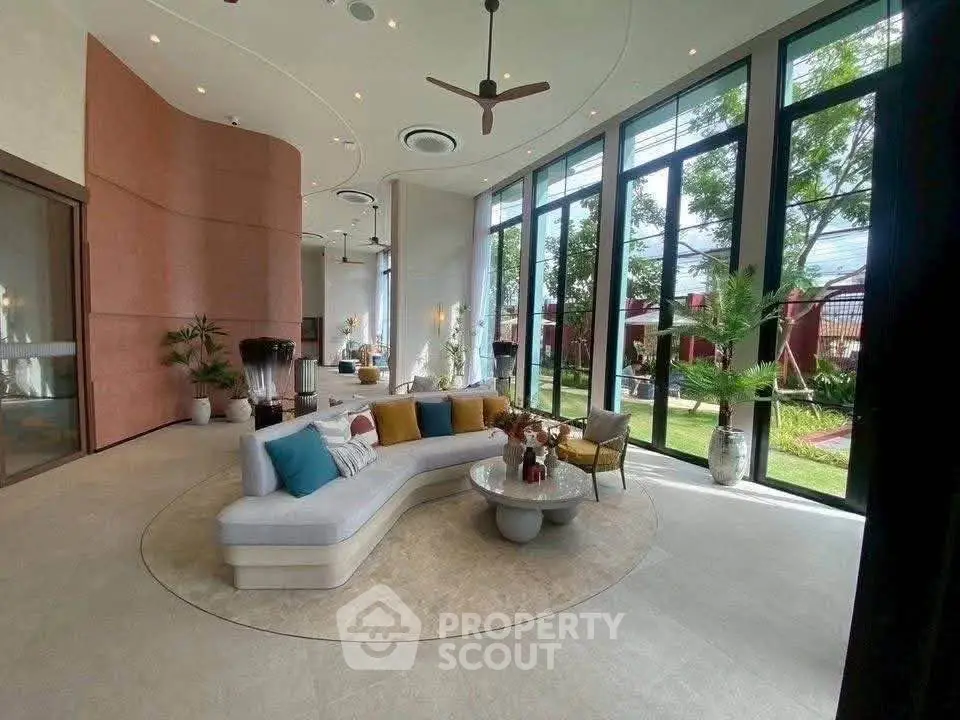Luxurious living room with floor-to-ceiling windows and garden view, featuring modern furniture and elegant decor.