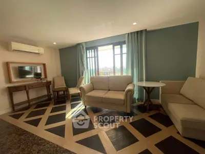 Spacious living room with elegant parquet flooring and large windows offering natural light.