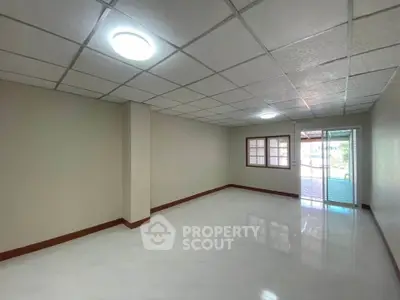 Spacious empty room with tiled floor and large window, ideal for customization.