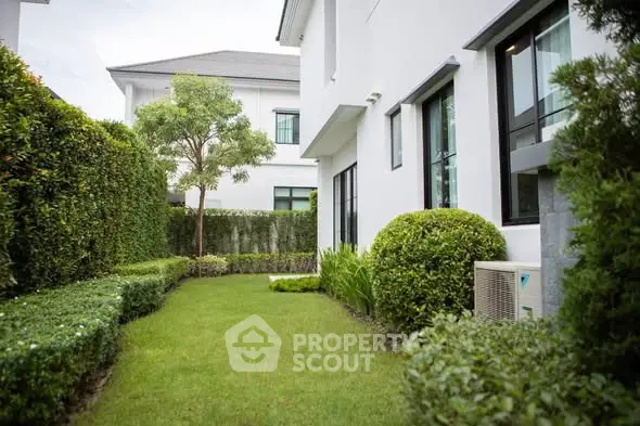 Charming garden view of modern white house with lush greenery and manicured lawn.