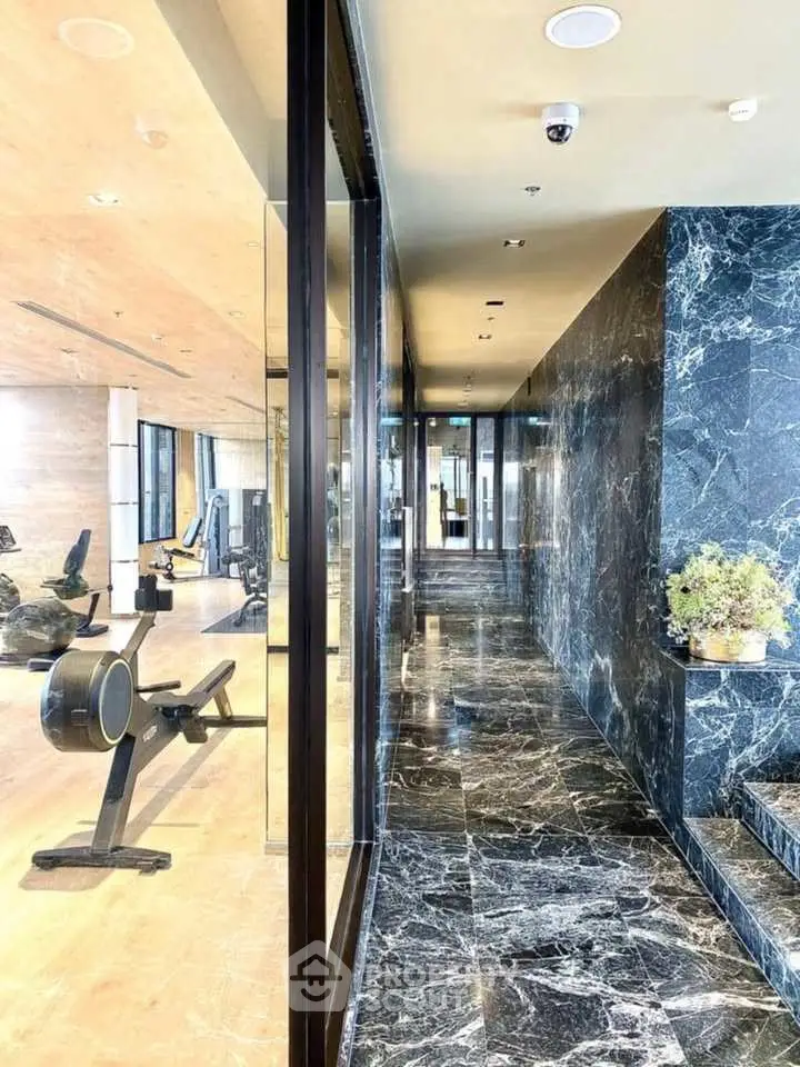 Luxurious gym with marble flooring and modern fitness equipment in upscale building.