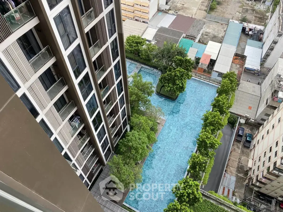 Stunning aerial view of modern high-rise building with luxurious swimming pool and lush greenery.