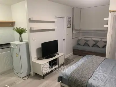 Cozy studio apartment with modern decor, featuring a comfortable bed, TV, and compact kitchen area.