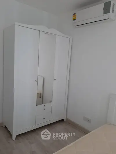Cozy bedroom with white wardrobe and air conditioning unit, perfect for comfortable living.