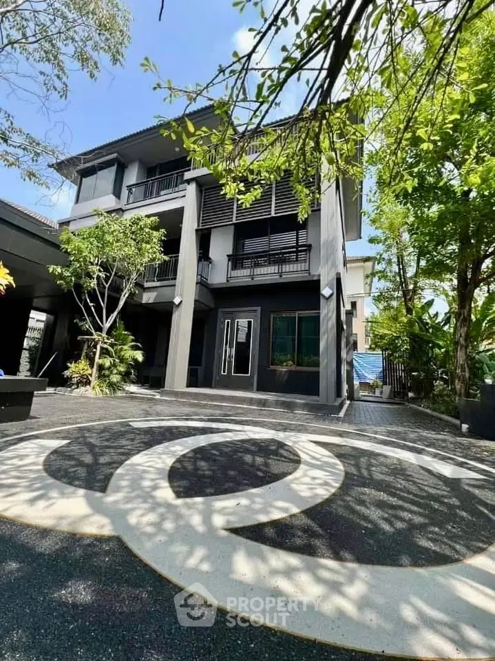 Modern three-story building with stylish facade and lush greenery, perfect for luxury living.