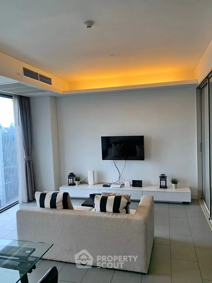 Modern living room with sleek design, featuring a wall-mounted TV and ambient lighting.